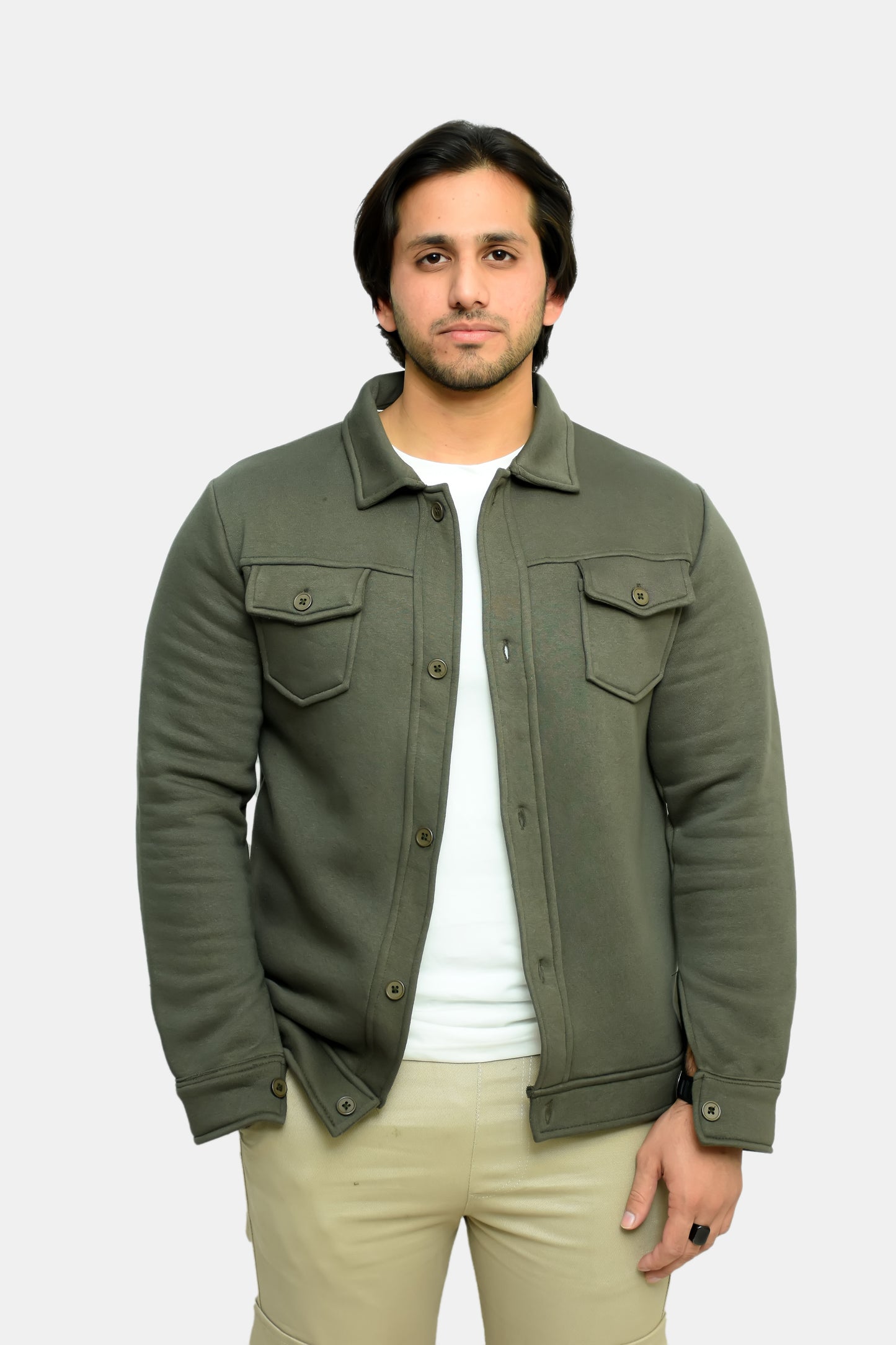 A man wearing a green trucker jacket with shirt and trousers, standing against a white background.